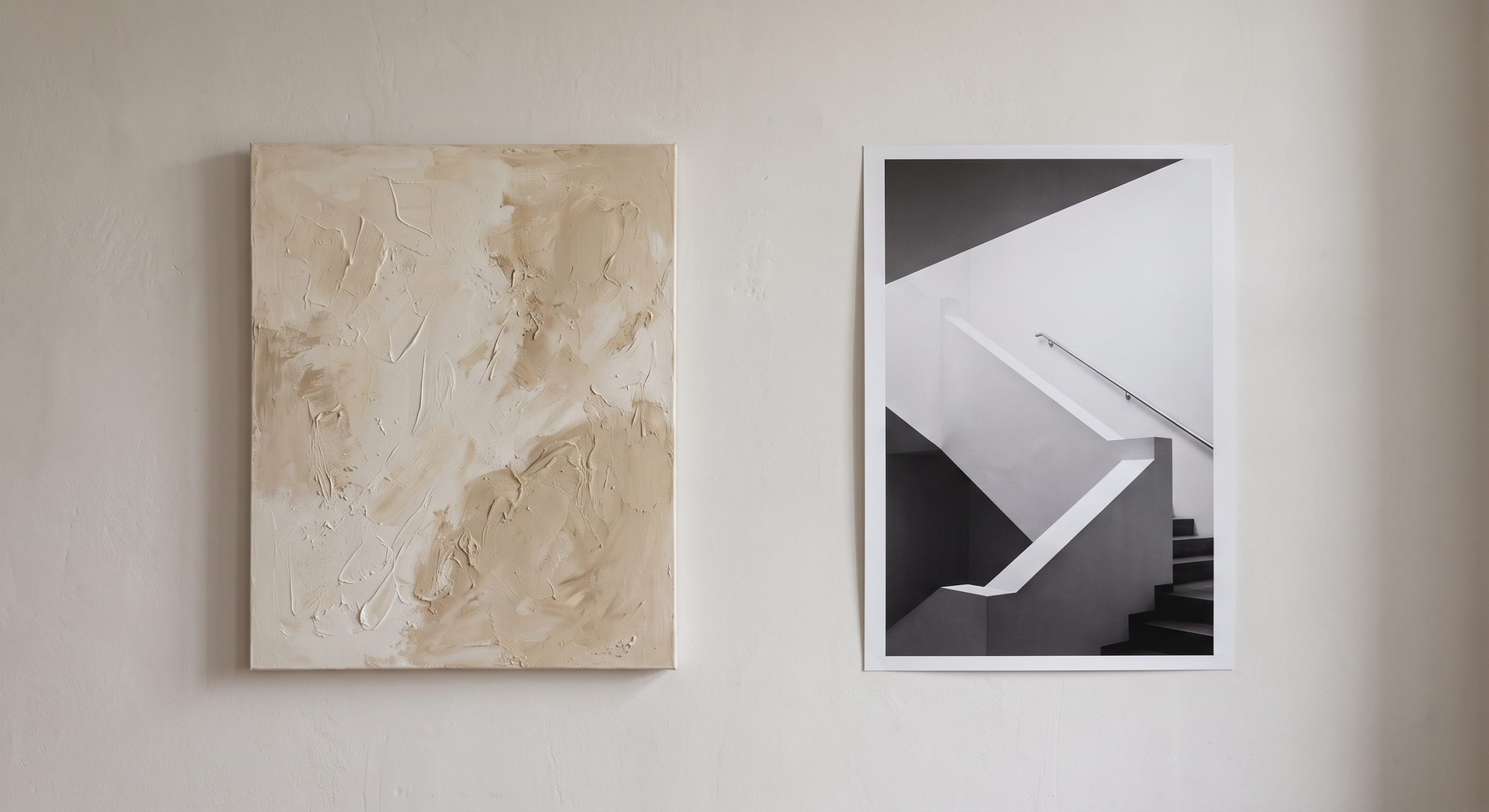 Textured abstract painting beside a black-and-white architectural photograph on a plain wall