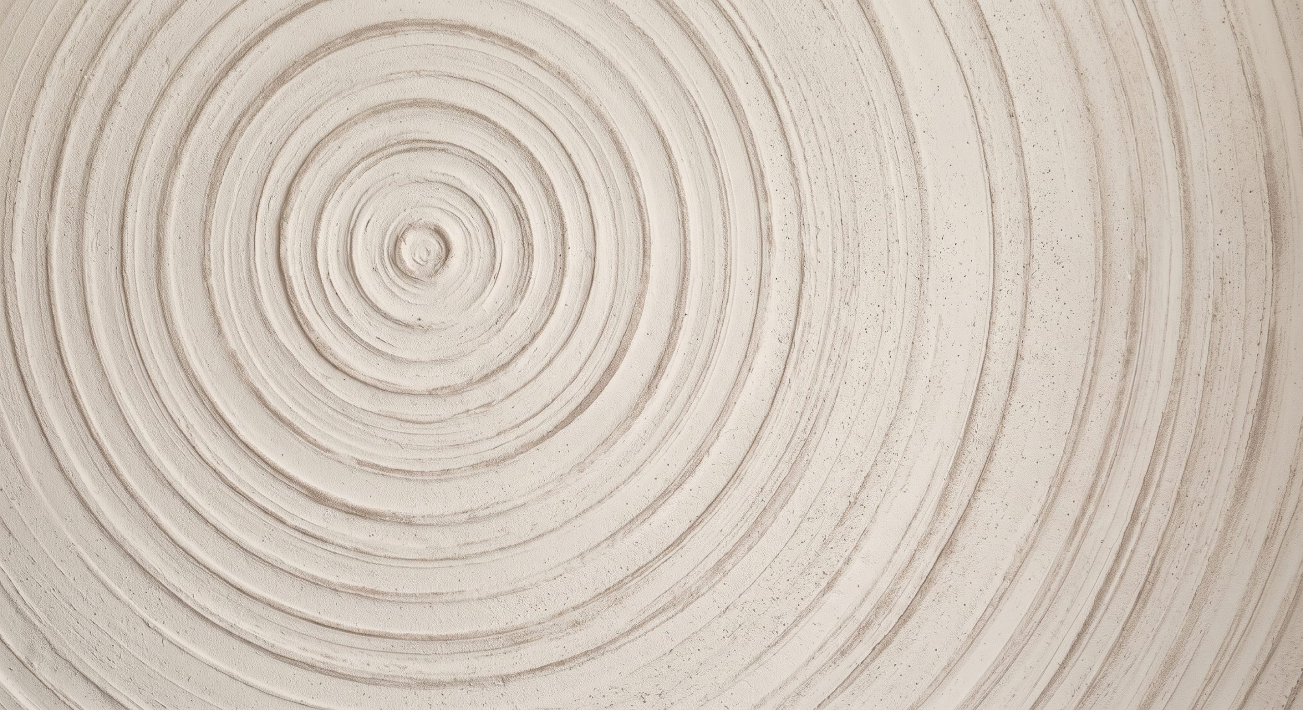 Radial abstract artwork with concentric ripple-like rings on a textured plaster surface