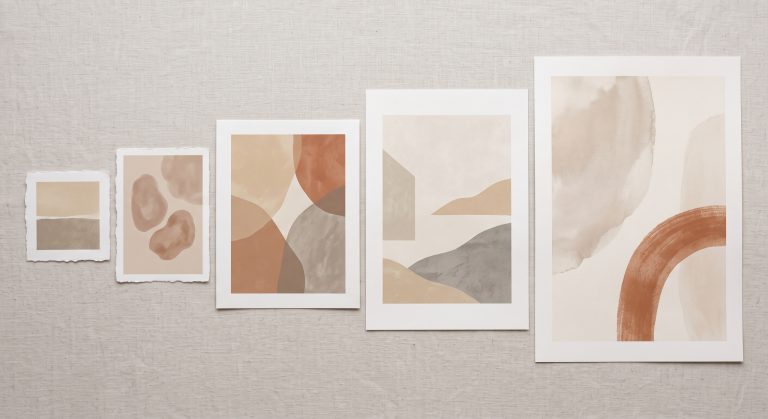Flat lay of several different sized art prints arranged from small to large