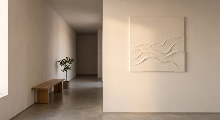 Large abstract artwork made from layered lime plaster in warm ivory and oatmeal tones with one darker fissure