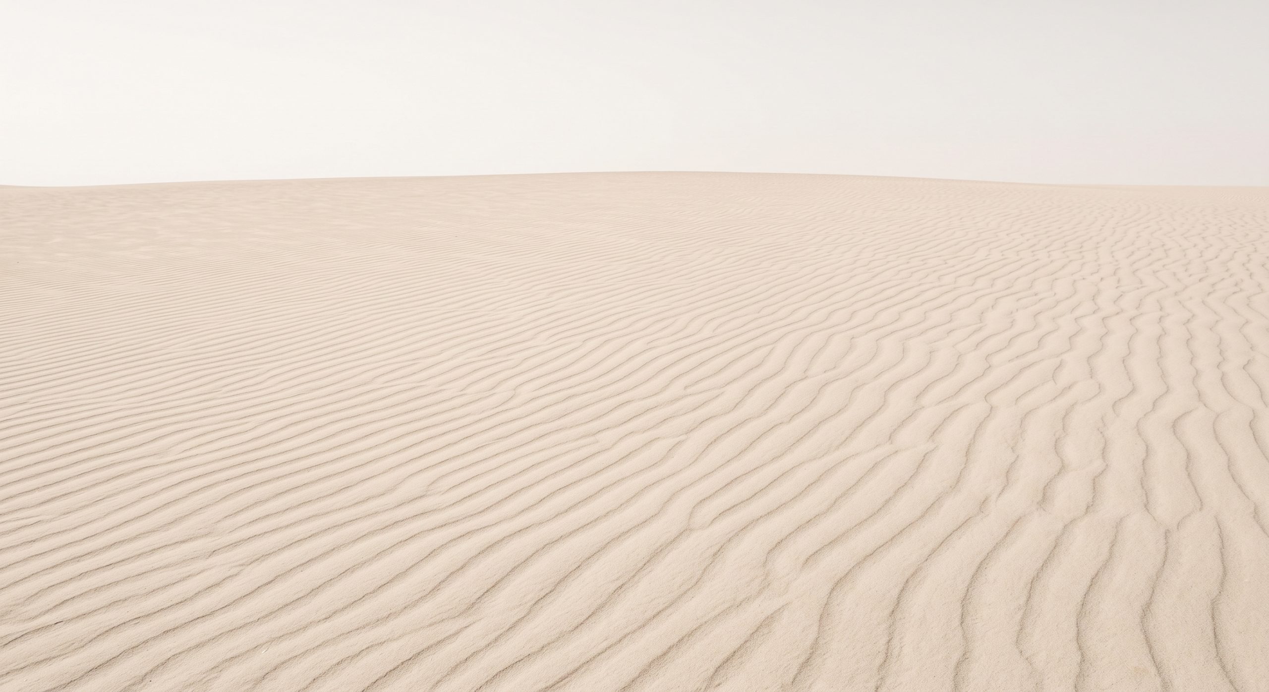 Minimalist fine-art photograph of soft sand dune ripples in pale beige tones